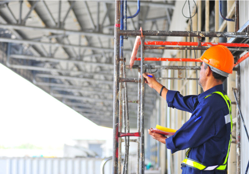 Foreman inspecting scaffolding structure at construction site