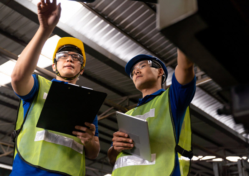 Two male engineers checking the machine inside a factory