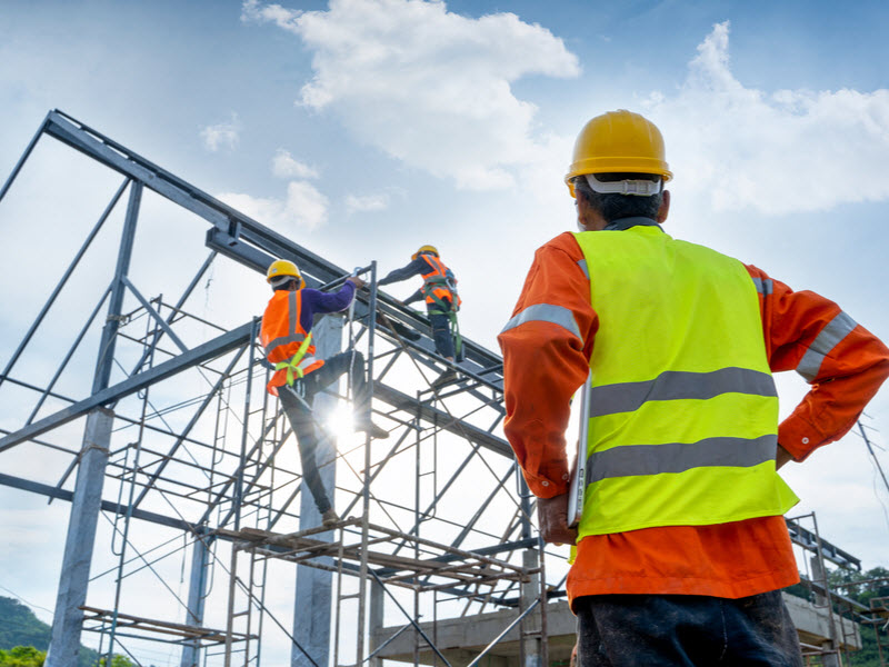 Engineer technician watching team of workers on high steel platform