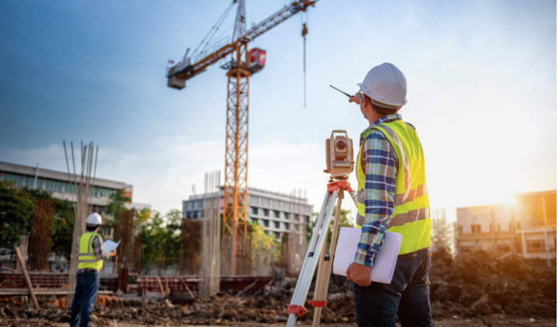 Engineer with surveyor telescope at construction site